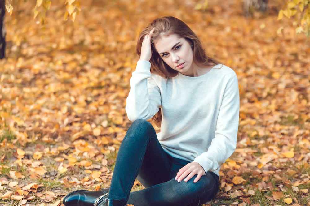 Woman sitting on some fallen leaves